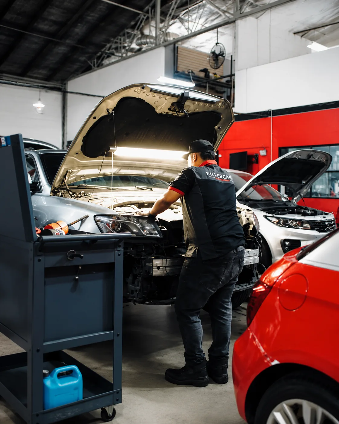 Técnico de Silver Cars revisando el vano motor de un vehículo en las bahías del taller en Medellín.